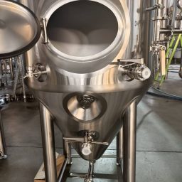 Stainless steel fermentation tanks in a brewery, showcasing various features and equipment.